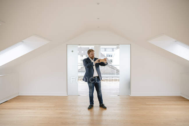 Estate agent standing in empty apartement taking pictures — Stock Photo
