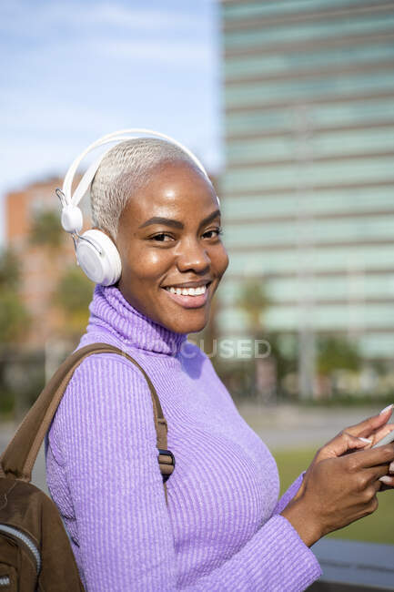 Porträt einer weißhaarigen Frau mit weißen Kopfhörern, die in der Stadt Musik hört — Stockfoto