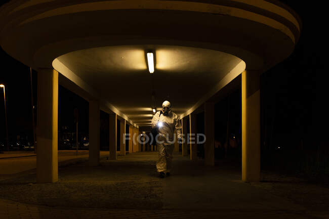 Seniorin in Schutzanzug und Maske nachts in der Stadt — Stockfoto