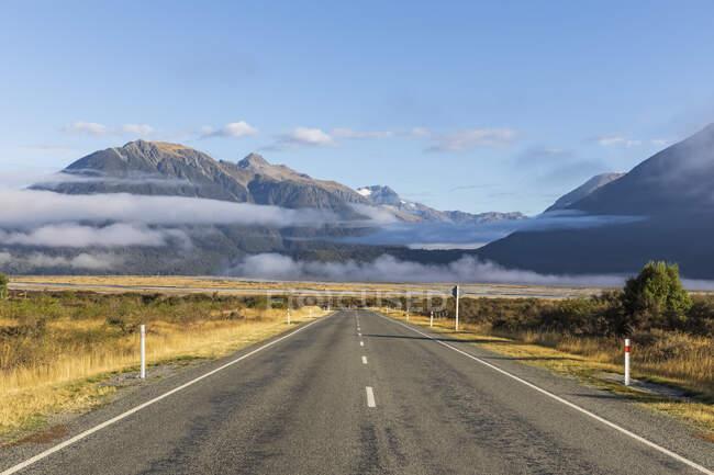 Nuova Zelanda, nebbia che galleggia sulla Statale 73 vuota con montagne sullo sfondo — Foto stock