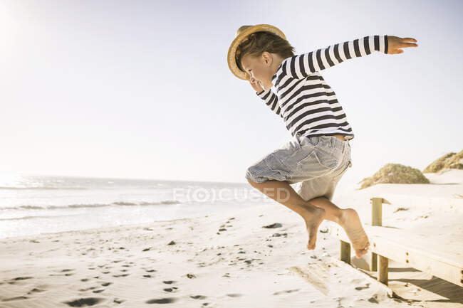 Junge mit Hut springt am Strand — Stockfoto
