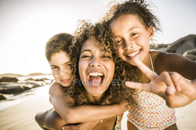 Portrait of a happy mother with her two kids having fun on the beach — Stock Photo