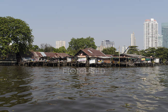 Cabanes à la rivière Chao Phraya, immeubles de grande hauteur en arrière-plan, Bangkok, Thaïlande — Photo de stock