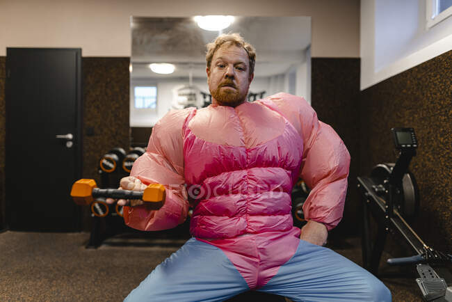 Mann im Fitnessstudio trägt pinkfarbenes Bodybuilder-Kostüm beim Hantelheben — Stockfoto