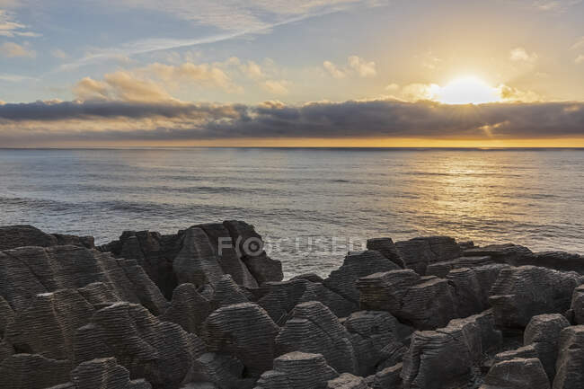 Nouvelle-Zélande, district de Buller, Punakaiki, formation de crêpes calcaires et trou de soufflage côtier au coucher du soleil — Photo de stock