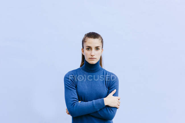 Портрет молодої жінки в синьому пуловері черепашки перед світло-блакитною стіною — стокове фото