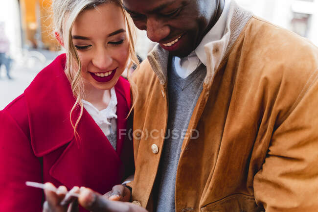 Sorrindo jovem casal compartilhando telefone celular — Fotografia de Stock