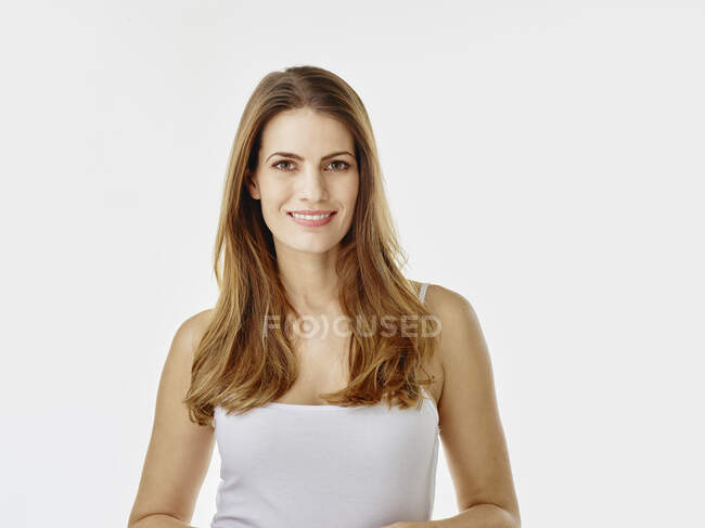 Retrato de mujer sonriente con el pelo largo sobre fondo blanco - foto de stock