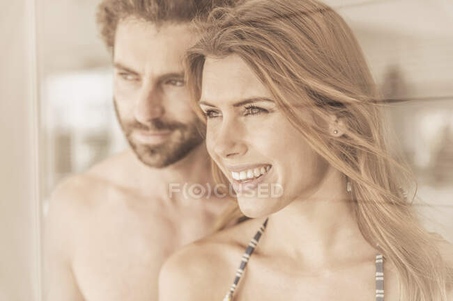 Feliz joven pareja mirando por la ventana - foto de stock