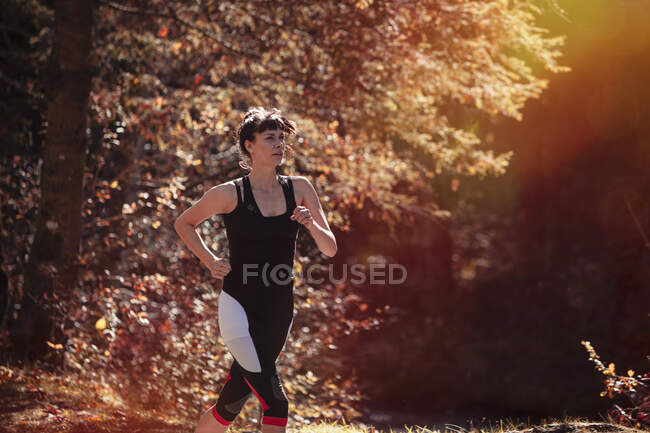 Жінка біжить в осінньому лісі — стокове фото