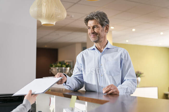 Patient handing over registration form at reception in a medical practice — Stock Photo