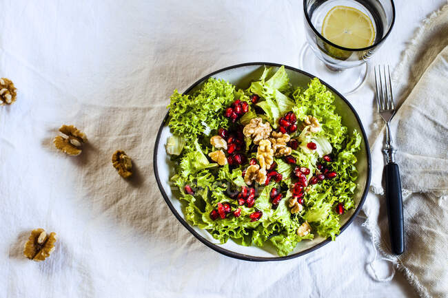 Bowl of green salad with walnuts and pomegranate seed — Stock Photo