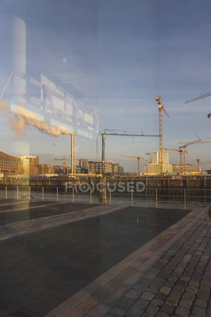 Germany, Hamburg, HafenCity harbor at dawn with smoke coming out of industrial chimneys in background — Stock Photo