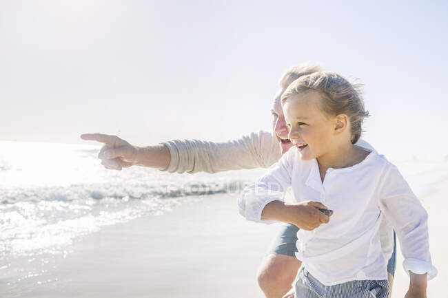 Pai se divertindo com seu filho na praia, apontando para a distância — Fotografia de Stock