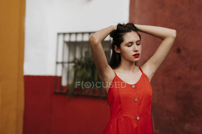 Portrait of female teenager wearing red strap dress, hands in hair — Photo de stock