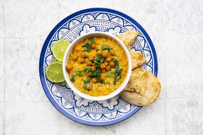 Curry vegano di lenticchie con lenticchie rosse, patate dolci, spinaci, curcuma arrosto, ceci, con succo di lime e coriandolo e pane naan — Foto stock