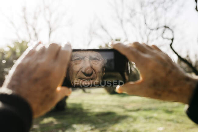 Vieil homme prenant des photos avec son smartphone — Photo de stock