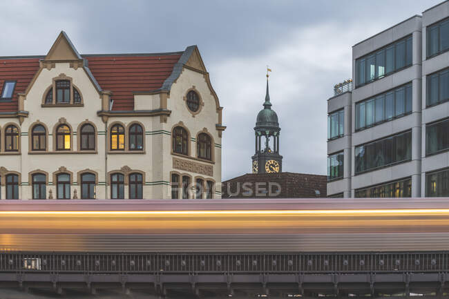Alemanha, Hamburgo, Movimento turvo de trem elevado passando edifício residencial com torre de Saint Michaels Igreja no fundo — Fotografia de Stock