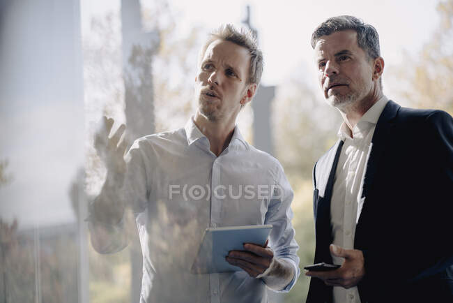 Два бизнесмена разговаривают у окна — стоковое фото