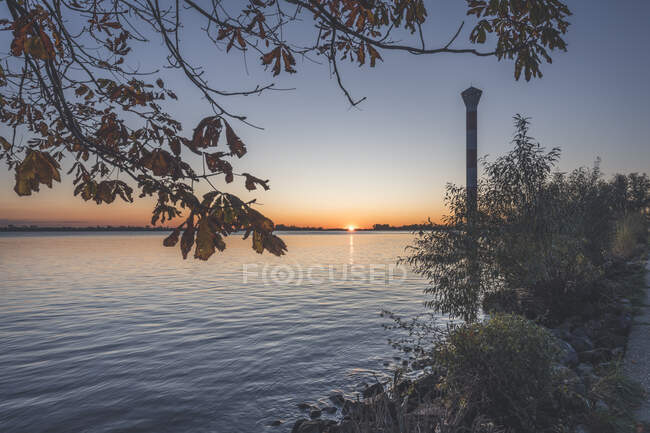 Germania, Amburgo, faro in piedi sulla riva del fiume Elba al tramonto — Foto stock