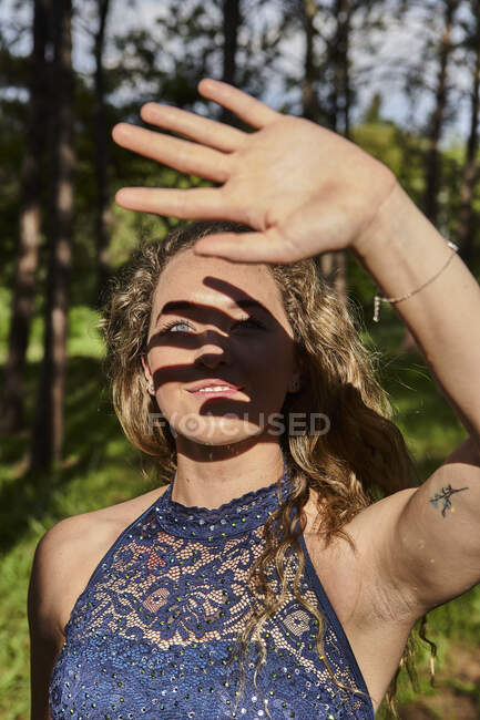 Souriante jeune femme protégeant les yeux avec sa main — Photo de stock
