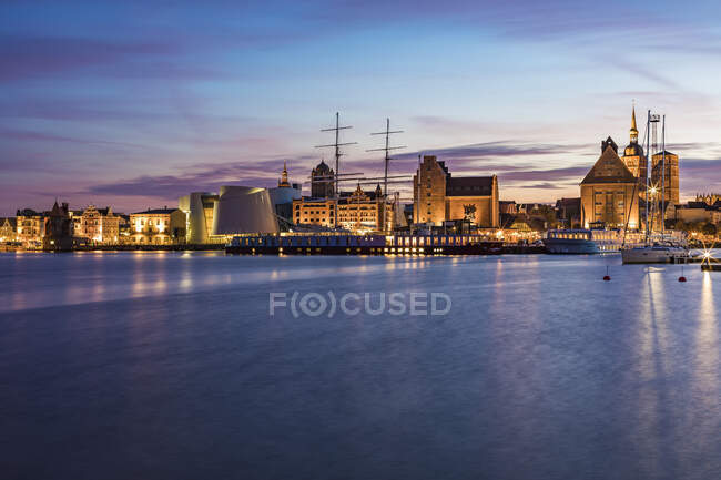 Germania, Meclemburgo-Pomerania occidentale, Stralsund, Lungomare della città costiera al tramonto con veliero e Ozeaneum sullo sfondo — Foto stock