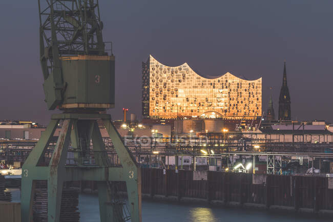 Germany, Hamburg, Harbor crane and Elbphilharmonie hall at dusk — Stock Photo