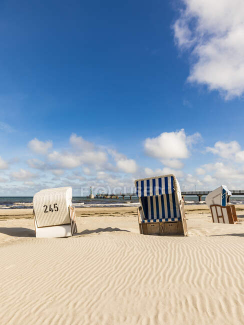 Germany, Mecklenburg-Western Pomerania, Strandkorb chairs on sandy coastal beach in summer — Stock Photo