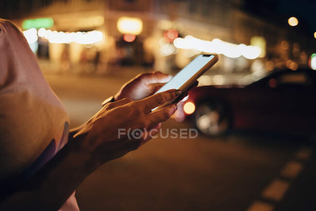 Mani di donna che tiene smartphone di notte, primo piano — Foto stock