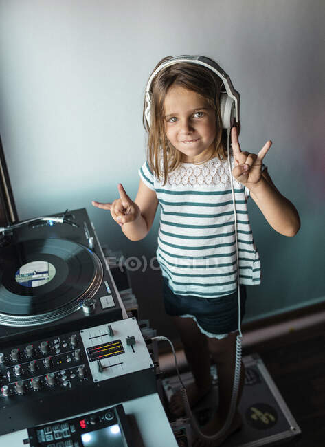 Retrato de la pequeña DJane con auriculares que muestran el signo de Rock and Roll — Stock Photo