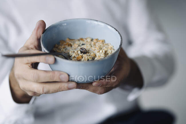Manos de hombre sosteniendo tazón de cereal, primer plano - foto de stock