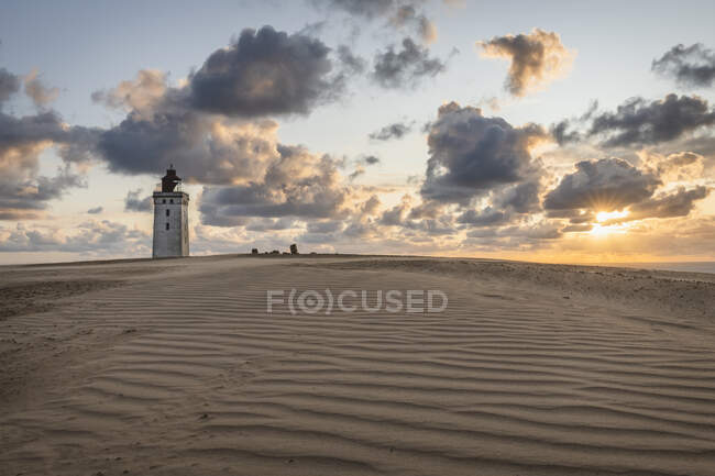 Danimarca, Lonstrup, Nuvole sulle dune di sabbia increspate e Faro di Rubjerg Knude al tramonto — Foto stock