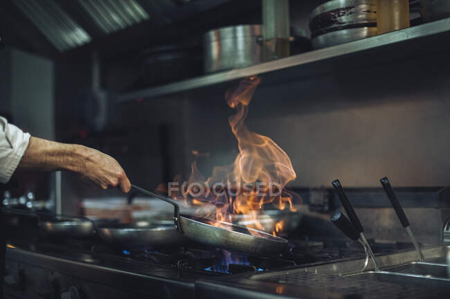 Шеф-повар готовит блюдо из фламба на газовой плите на кухне ресторана — стоковое фото