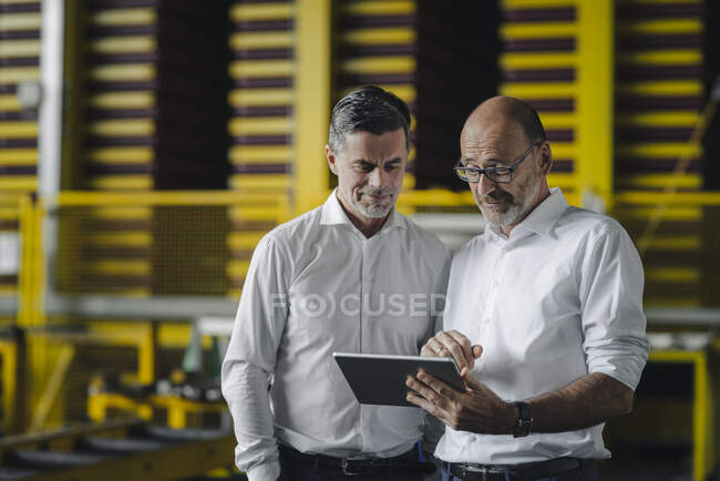 Two businessmen using tablet in a factory — Stock Photo
