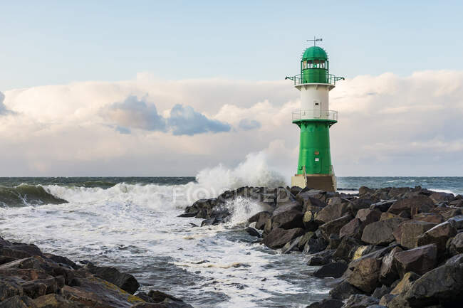 Alemanha, Mecklemburgo-Pomerânia Ocidental, Warnemunde, Farol e ondas do mar batendo contra rochas — Fotografia de Stock