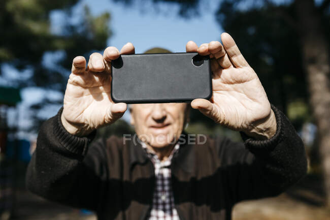 Vecchio che fa foto con il suo smartphone — Foto stock