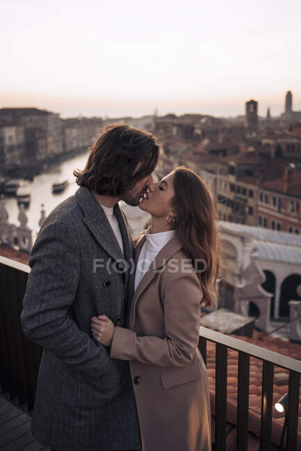 Привітна молода пара цілується на балконі над містом Венеція (Італія). — стокове фото