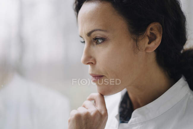 Medico donna in piedi alla finestra, guardando preoccupato — Foto stock