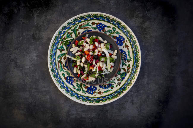 Plate ofcannellinibean salad with fennel, bell pepper, black olives, pomegranate seeds, mint and parsley — Stock Photo