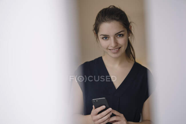 Retrato de una joven sonriente con teléfono móvil - foto de stock
