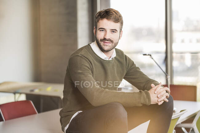 Retrato de um jovem empresário confiante sentado na mesa de conferência no escritório — Fotografia de Stock
