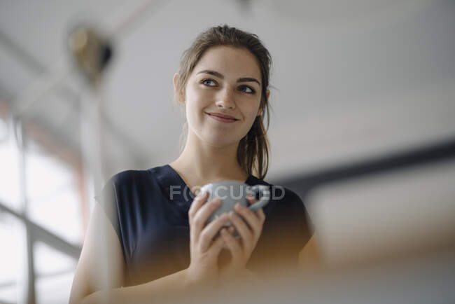 Ritratto di giovane donna sorridente con tazza di caffè in carica — Foto stock