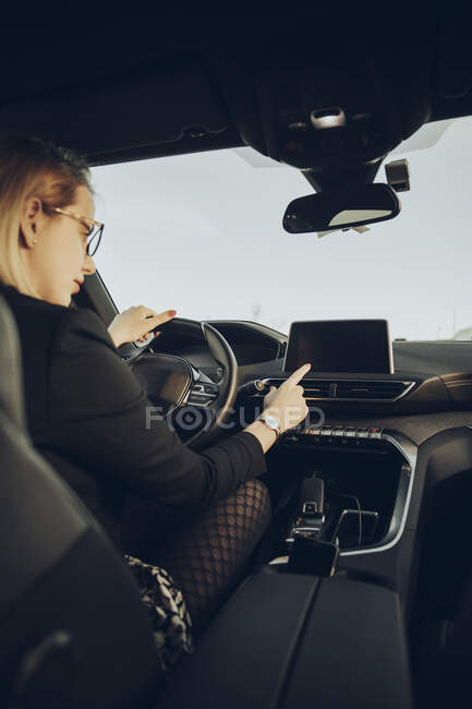 Mujer joven utilizando el dispositivo de navegación en el coche - foto de stock