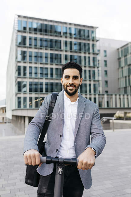 Retrato de un joven hombre de negocios casual con scooter eléctrico en la ciudad - foto de stock