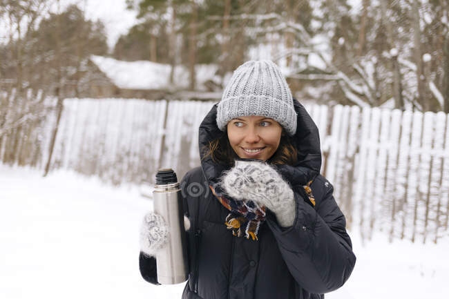 Портрет усміхненої жінки, що використовує термо колбу взимку — стокове фото