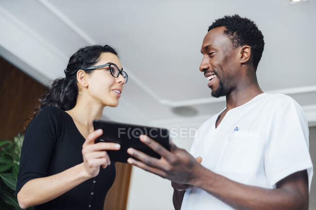 Dentista con tableta hablando con paciente femenino en cirugía dental - foto de stock