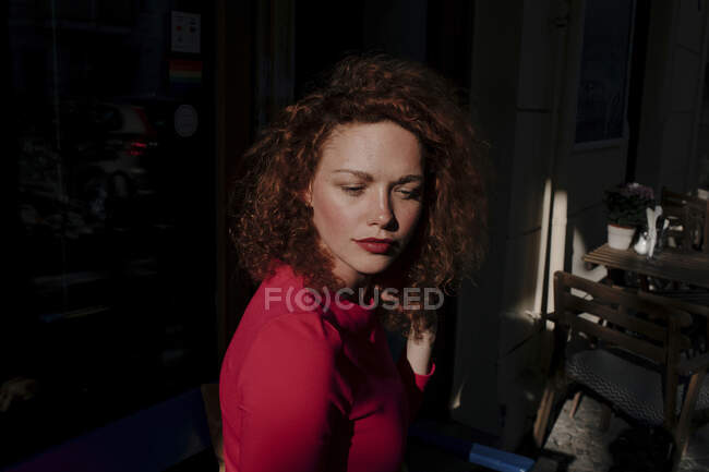 Retrato de una mujer pelirroja en un café, mirando hacia los lados - foto de stock