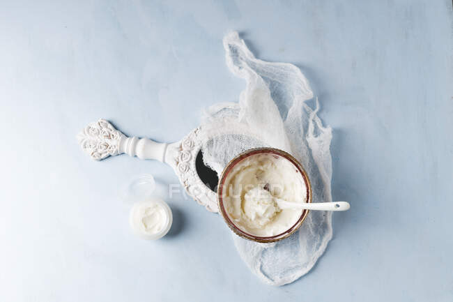 Gauze, hand mirror and bowl of homemade shea butter moisturizer — Stock Photo