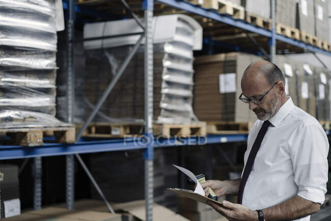 Mann mit Klemmbrett und Scanner in Fabrikhalle — Stockfoto