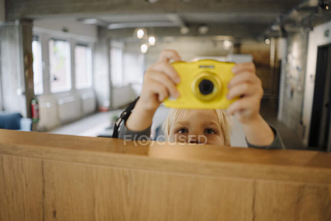 Garçon prendre une photo avec un appareil photo dans le bureau — Photo de stock
